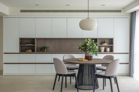 modern dining room has white built-in handleless cabinets and a round dining table