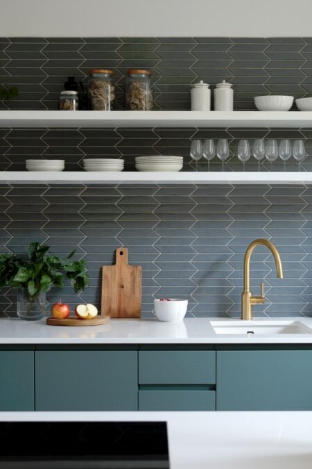 modern kitchen with gray backsplash and white floating shelves with tableware and glassware