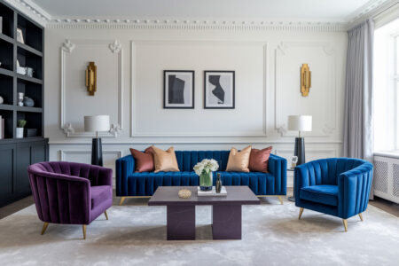 Art Deco style living room with white walls and moldings, blue channel tufted velvet sofa, purple and blue armchairs