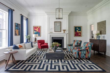 eclectic style living room with white walls and a couch, blue curtains, area rug with geometric pattern