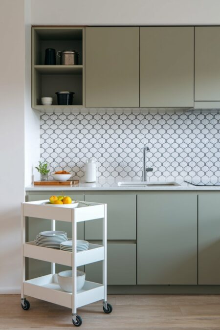 small sage green kitchen with a white rolling kitchen cart for storage