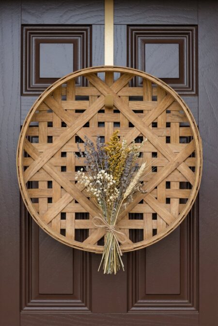 round woven tobacco basket with a bunch of dried wildflowers as spring door decor