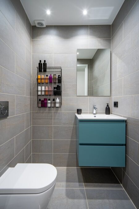 small bathroom with a wall-mounted black metal spice rack repurposed for bathroom storage