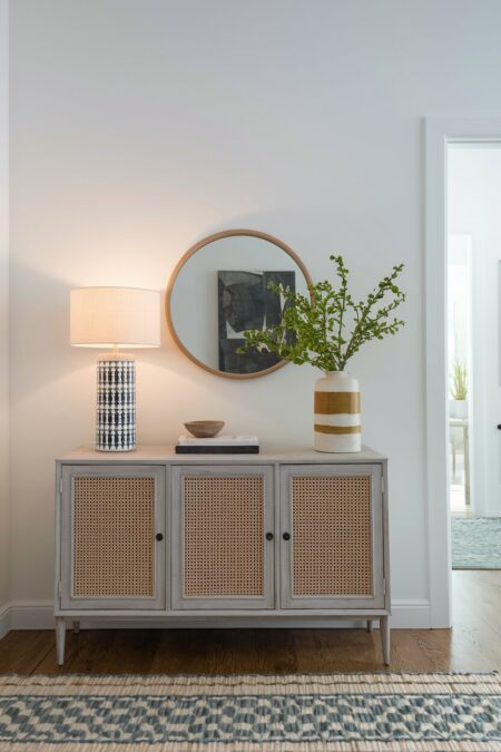 lamp with a linen shade and a vase with green branches on the console table as summer entryway decor
