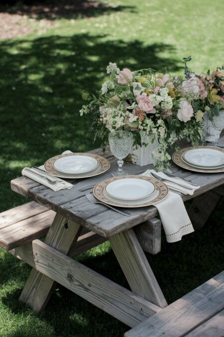 rustic wooden picnic table with fine china and cloth napkins as summer table decor