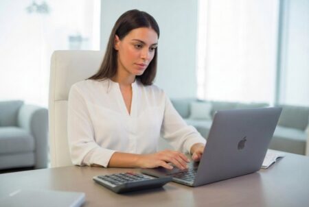 Side hustles for accountants. Young female accountant in white clothes working on a laptop.