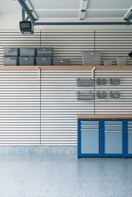 white slatwall panel system used for garage storage, floating shelf, wire baskets