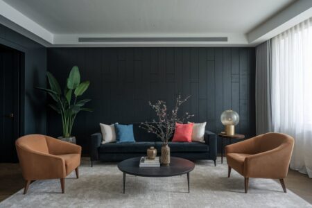 dark living room with velvet furniture, a light gray area rug, and color accents in throw pillows