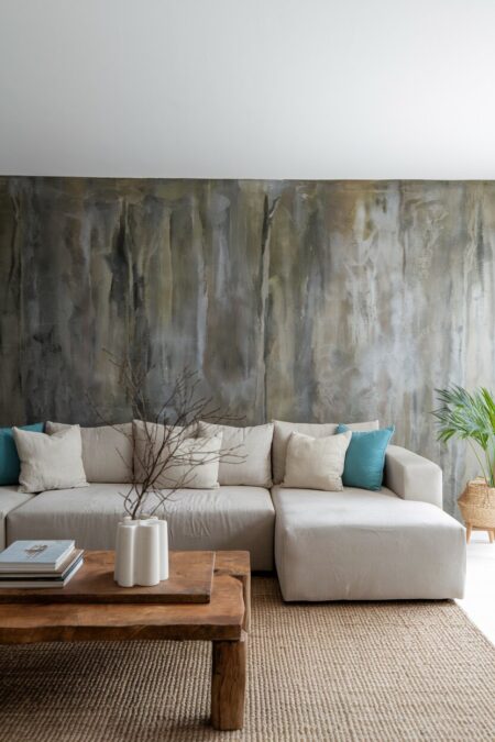 earthy living room with a concrete wall behind the modern neutral sofa and a wood coffee table