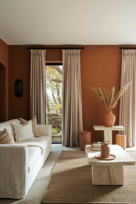 earthy living room with deep clay tone walls, light sofa upholstery, and a sisal rug