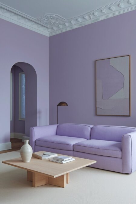 minimalist lavender living room with a two-seater sofa, large abstract artwork, and a light wood coffee table