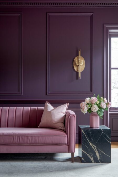 moody plum dark living room with a blush pink velvet sofa and black marble side table