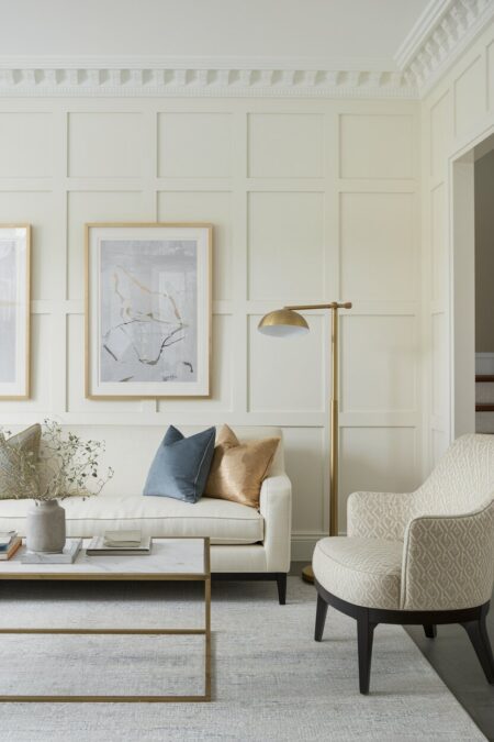 neutral living room with board and batten, a cream sofa, brass floor lamp and hardware