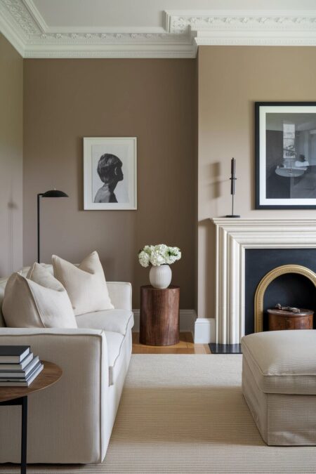 neutral living room with soft taupe walls, a light color sofa, a warm toned wood side table, and black accents
