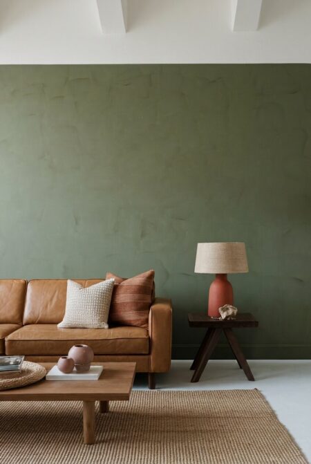 sage green living room with a leather couch and terracotta decor