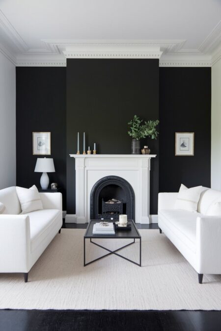 black and white living room with a matte black accent wall behind a fireplace