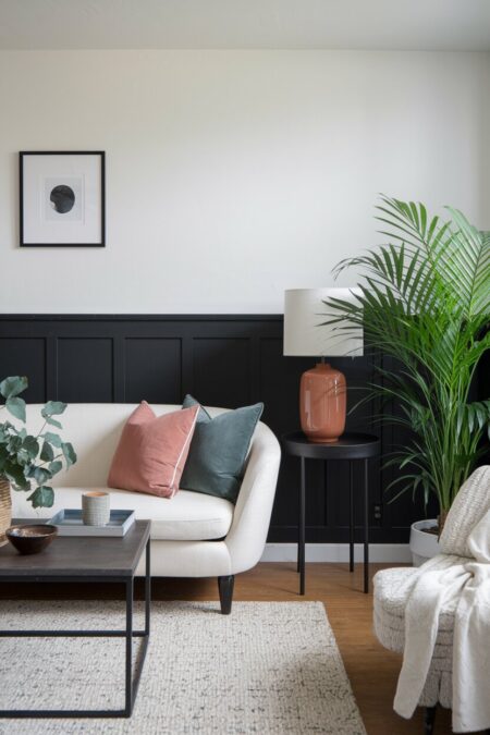 black and white living room with sage green and dusty rose throw pillows, and a ceramic table lamp