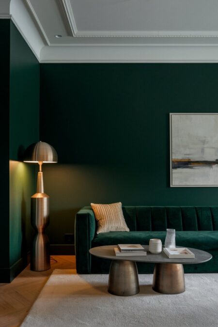 dark green living room with a statement brushed brass floor lamp and velvet sofa