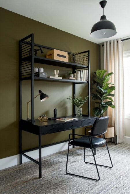 deep olive green home office with a black chair, desk, and metal shelving