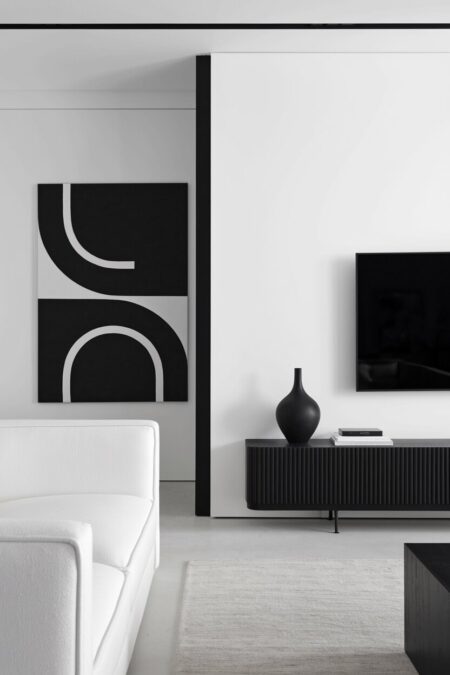 minimalist black and white living room with an abstract artwork, a black media console, and a TV