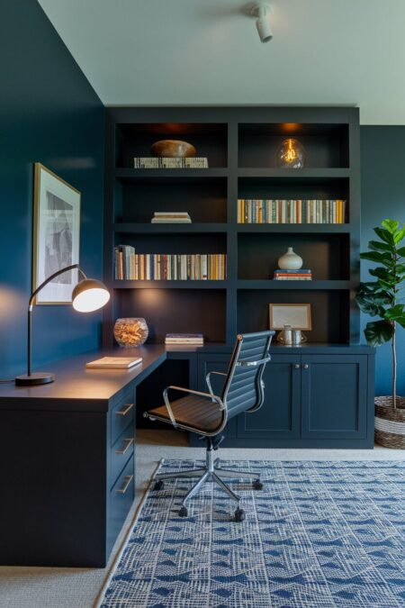 moody blue home office with dark charcoal furniture, corner desk