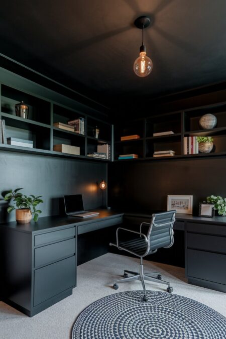 all-black dark home office with a corner desk and shelves above