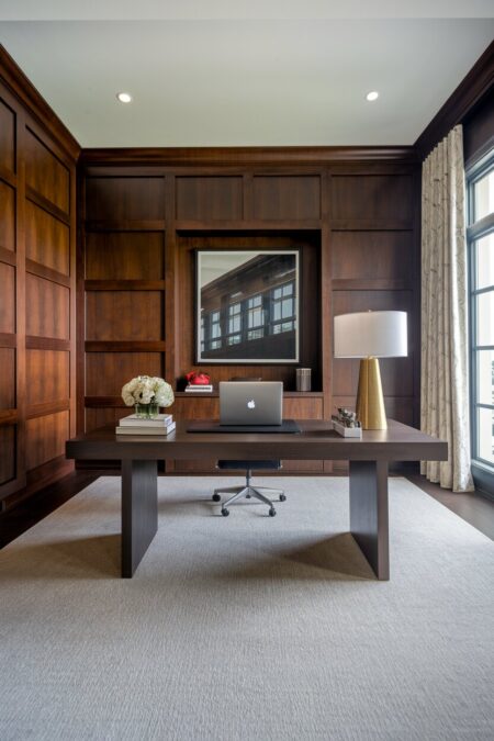 luxury home office with rich wood wall paneling and brass table lamp base