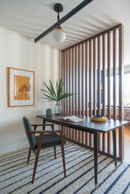 mid-century modern home office with a wood slat room divider, a gray chair, and a striped rug