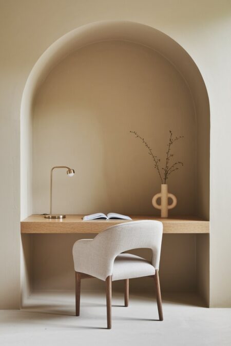 minimalist beige home office with an oak desk in the alcove and a small ceramic vase