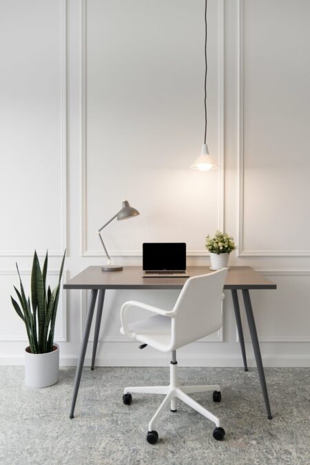 minimalist white home office with a matte gray desk, pendant light, and a white office chair