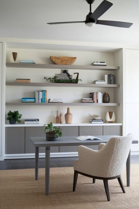 neutral modern home office with built-in shelving and a boucle accent chair