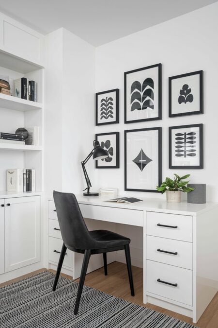 white home office with a black chair, desk lamp, and artwork