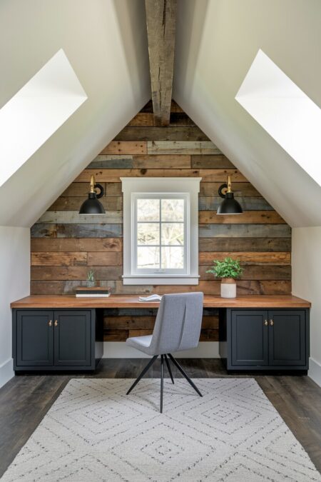 attic home office with reclaimed wood paneling, black wall sconces and desk cabinets