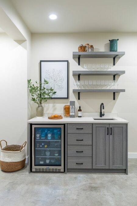 basement has a small beverage station with a mini fridge, a small sink, and a few floating shelves above
