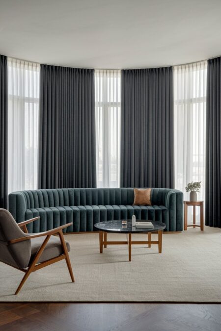 luxury living room with a channel tufted velvet sofa and gray floor-to-ceiling drapery