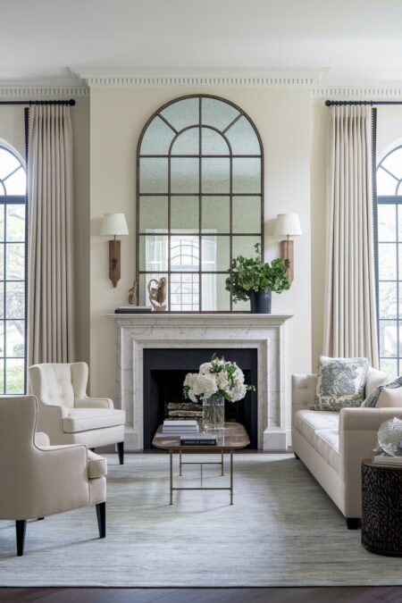 luxury living room with an arched oversize mirror above the marble fireplace