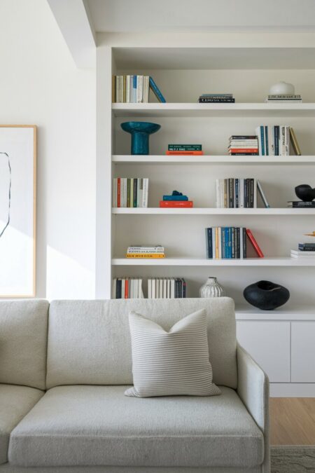 minimalist living room has built-in white shelving with books and decor