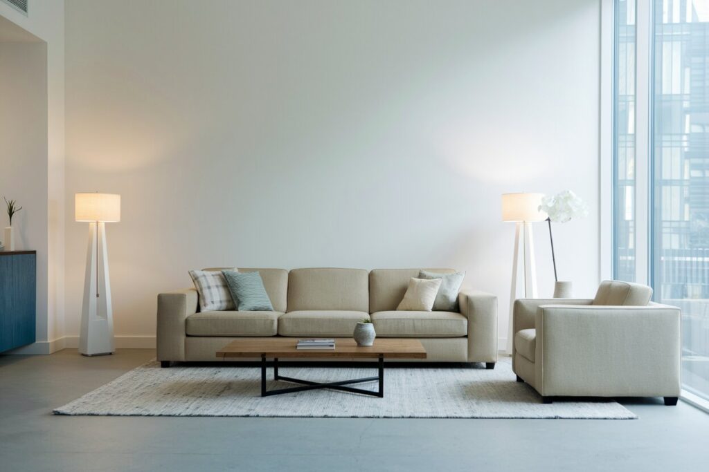 minimalist living room with white walls, a couch, upholstered armchair, and two floor lamps