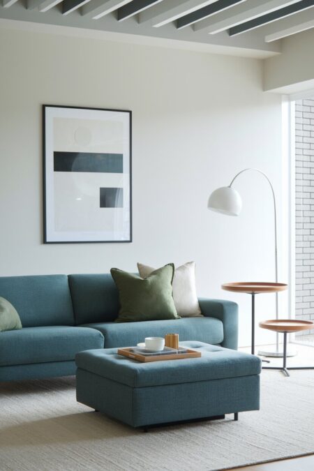 minimalist living room with a muted blue sofa and storage ottoman