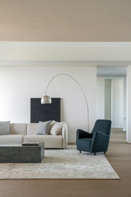 minimalist living room with white walls, neutral sofa, and a dark sculptural accent chair