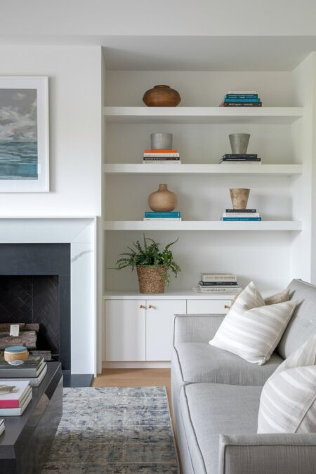 modern living room with white built-in shelves with some negative space and cabinets around a fireplace