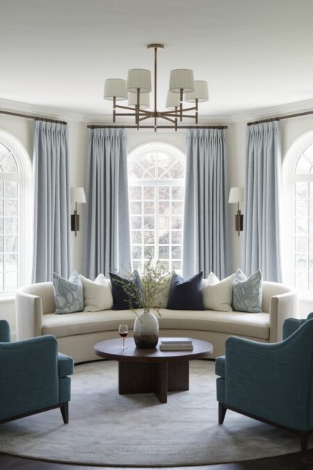 romantic living room with a cream curved sofa, light blue curtains, a wooden coffee table, and blue-gray armchairs