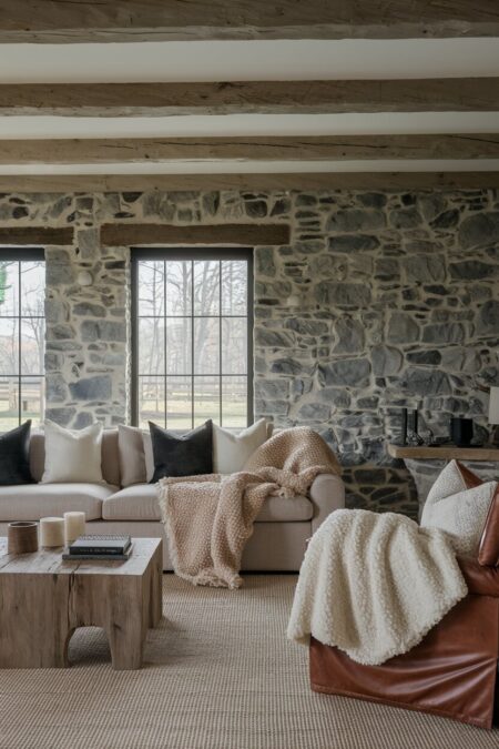 rustic living room with a stone wall and warm, soft textiles in a muted palette