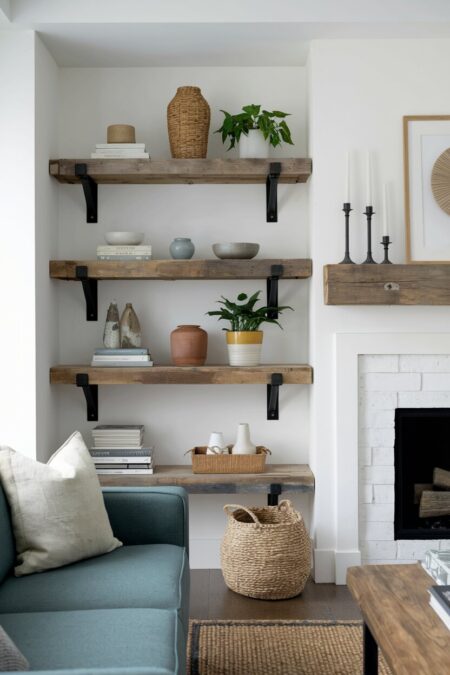 rustic living room with open shelves made of simple wood planks on iron brackets wall-mounted next to the fireplace