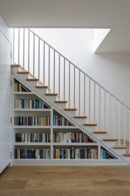 white built-in bookshelves under the stairs