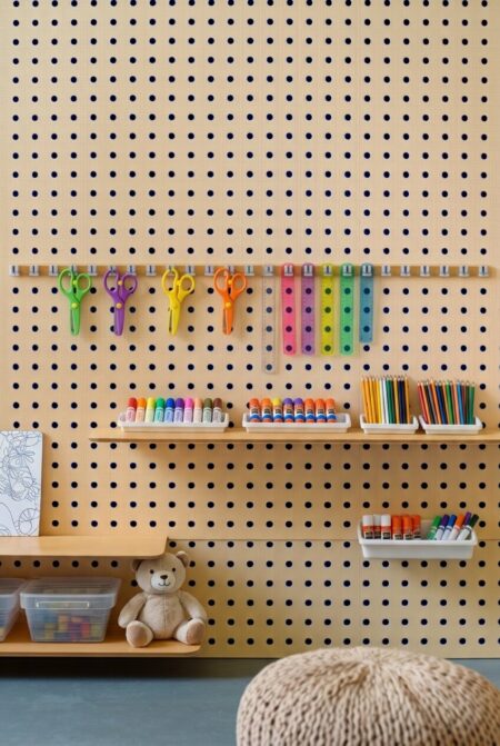 wooden pegboard with shelves and art supplies in the playroom