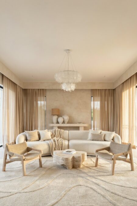 sandy neutral beach house living room with beige micro cement wall finish, a cream boucle sofa, and a travertine coffee table