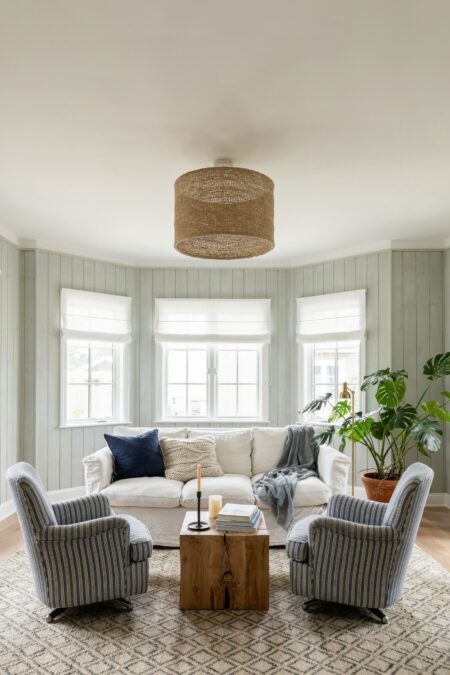 beach house living room with sage green wash shiplap walls, a white slipcovered sofa, two armchairs, and a square cedar wood coffee table