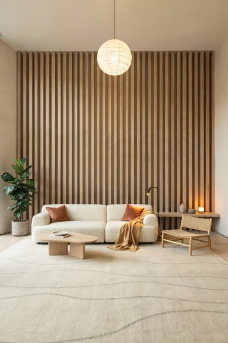 Japandi living room with a feature wall of oak floor-to-ceiling vertical slats and a cream boucle modular sofa