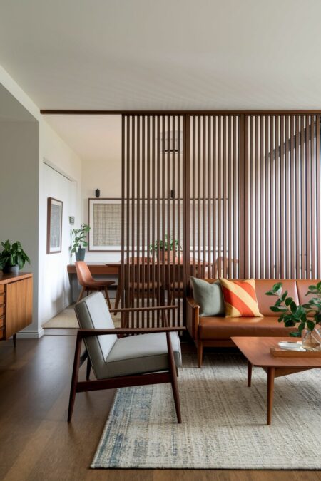 mid-century modern living room with a slatted wood room divider behind the sofa and dining area behind it